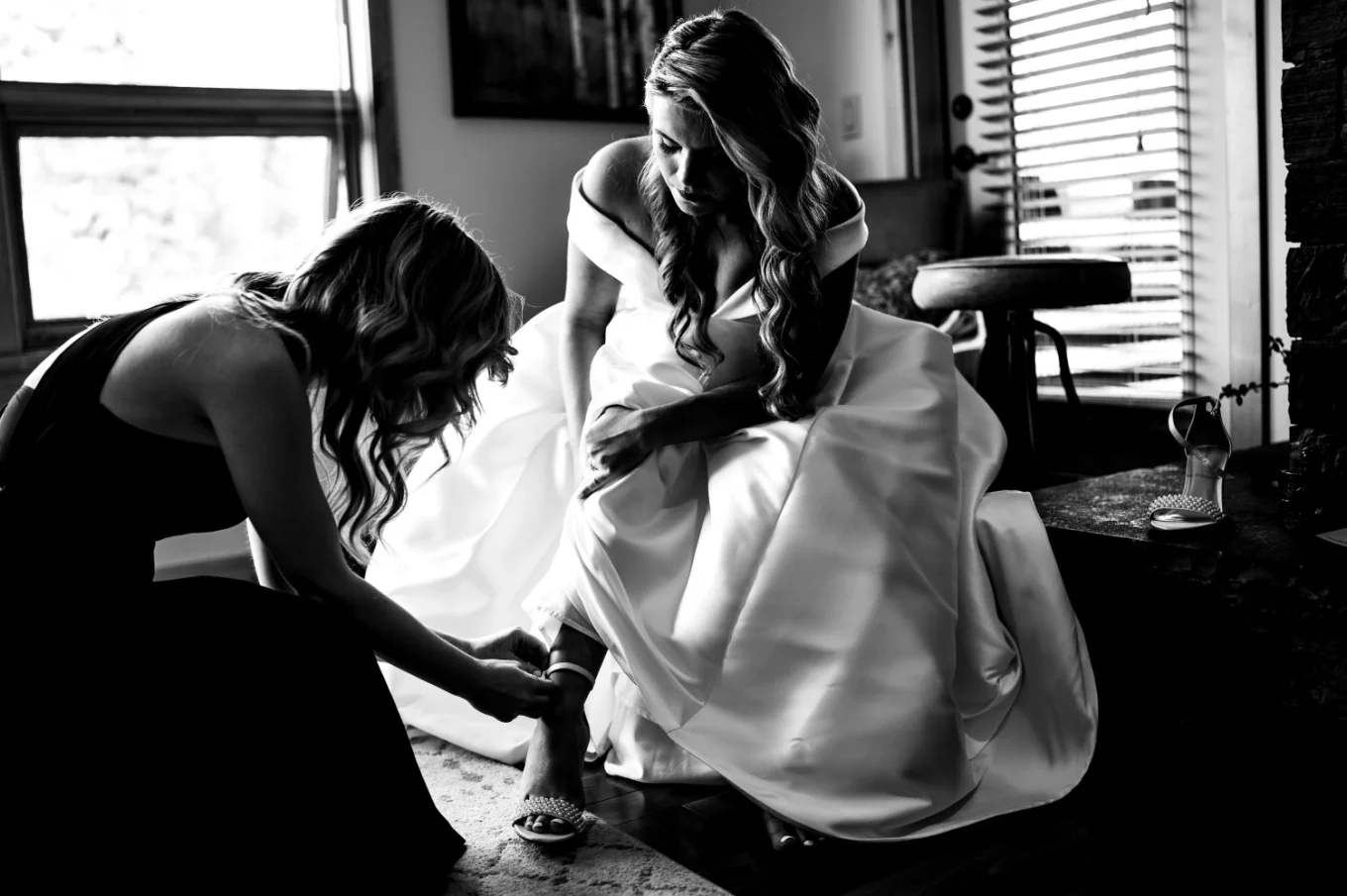 Bridesmaid put the wedding shoe on the brides leg before elopement in Banff.