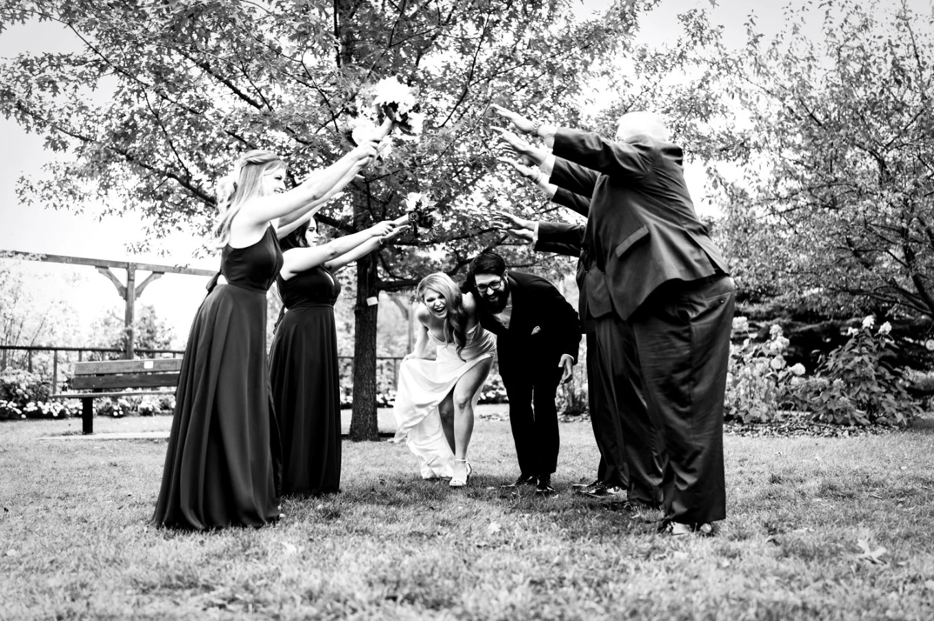 Newlyweds run under the hand bridge created by wedding party in Edmonton