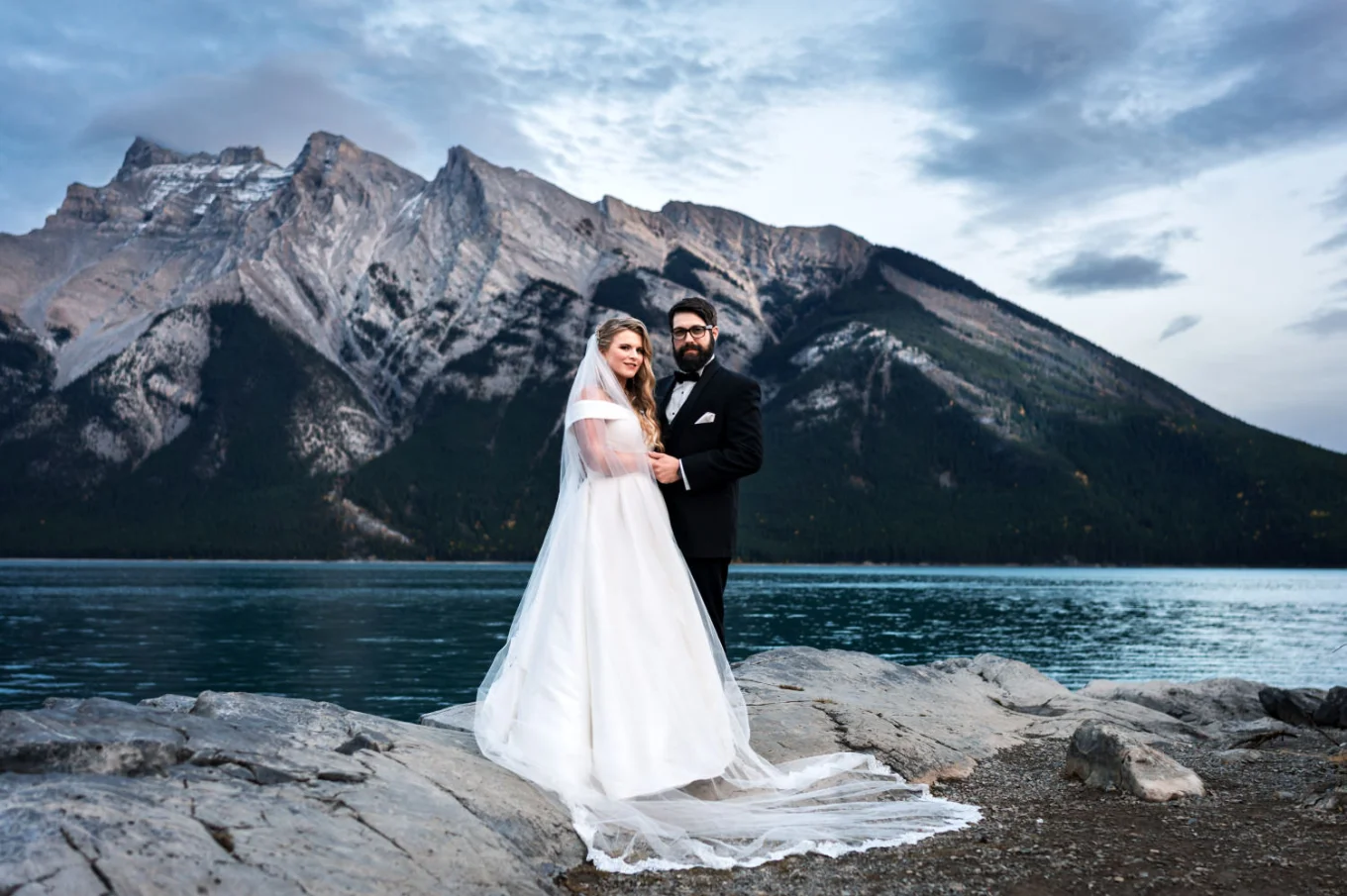 Banff Elopement Portrait at Minnewanka Lake with the bride and groom looking at the camera.