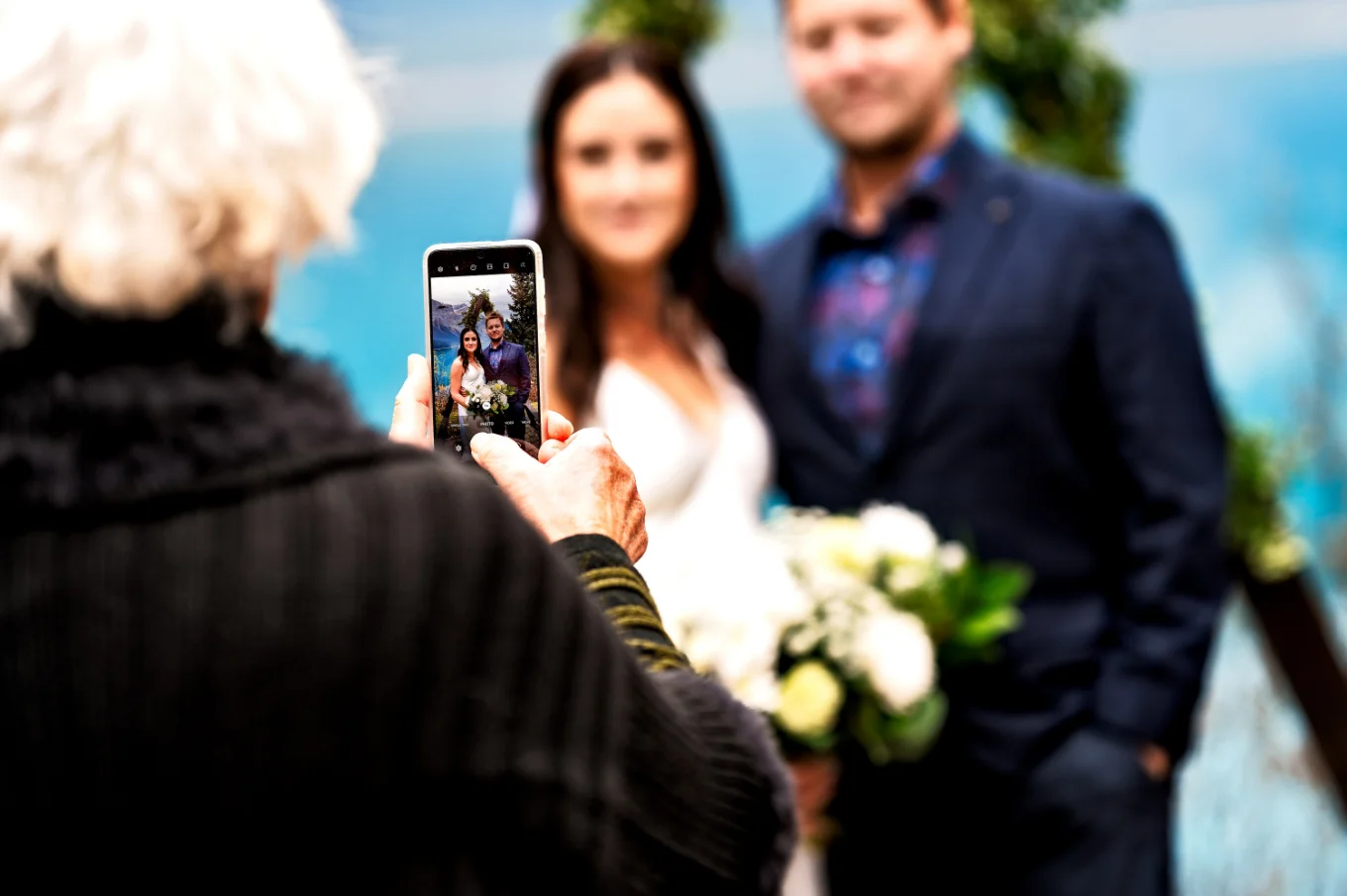 Mather of the bride takes a photo of the bride and groom at the wedding