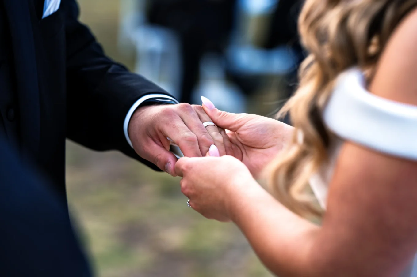 Bride puts a wedding ring on the grooms finger.