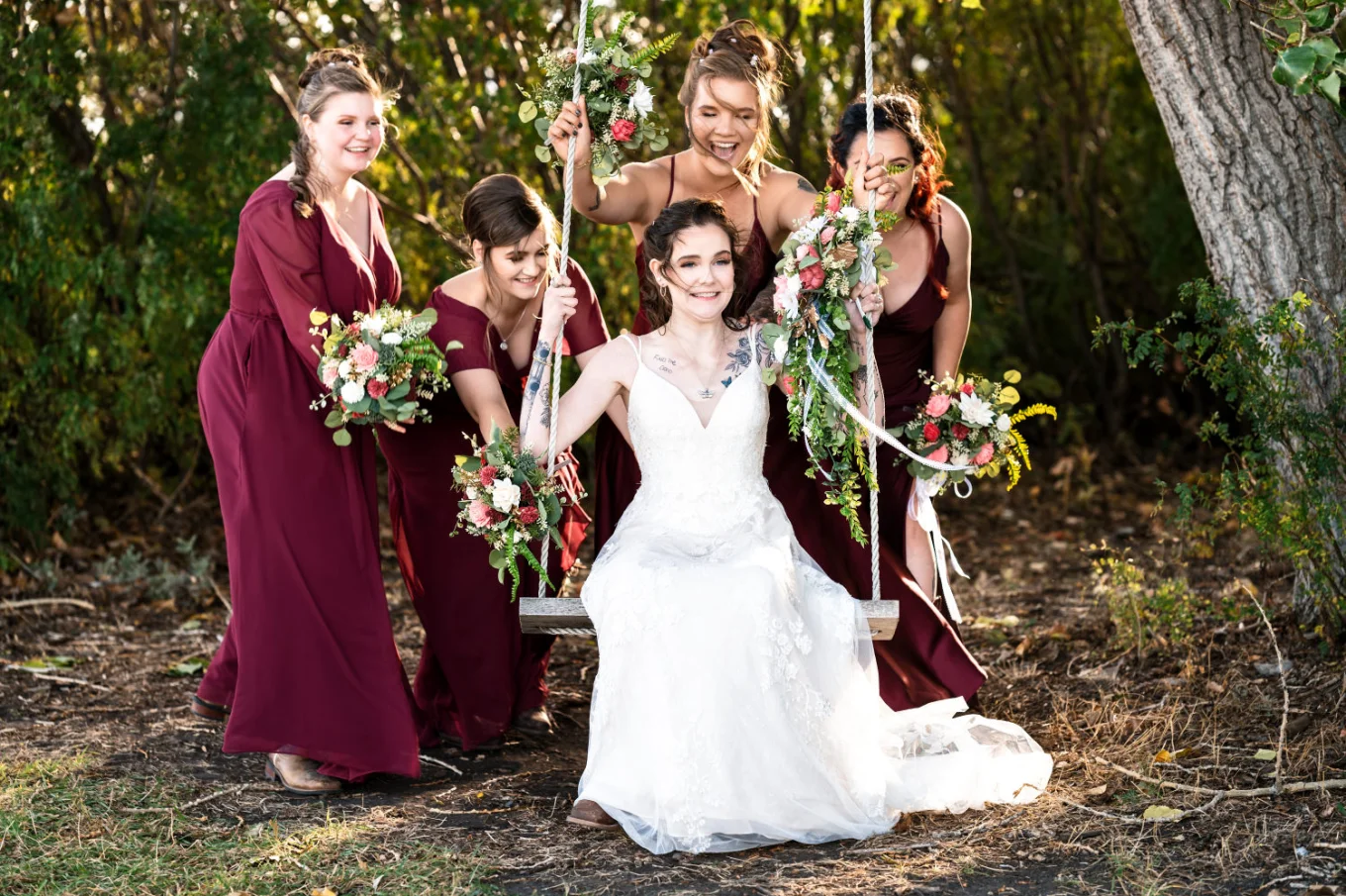 Bridal party swing the bride on the swing. They are having fun an the wedding day in Calgary.