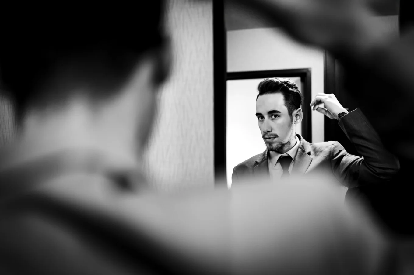 The groom brushes his hair in front of the mirror.