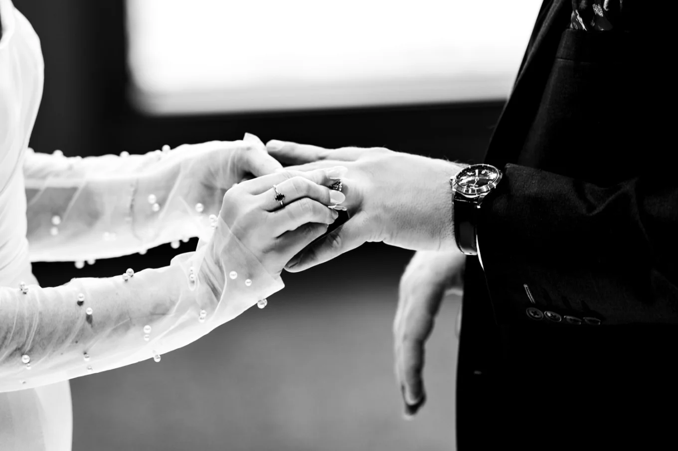 hands of the newlyweds exchanging wedding rings
