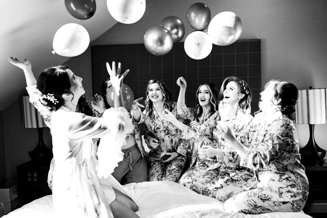 wedding party plays with the balloons on the bed in pyjamas