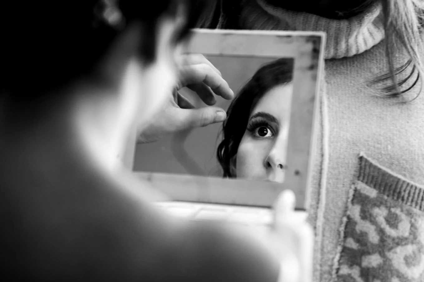 Brides reflection in the mirror while she fixes her hair.