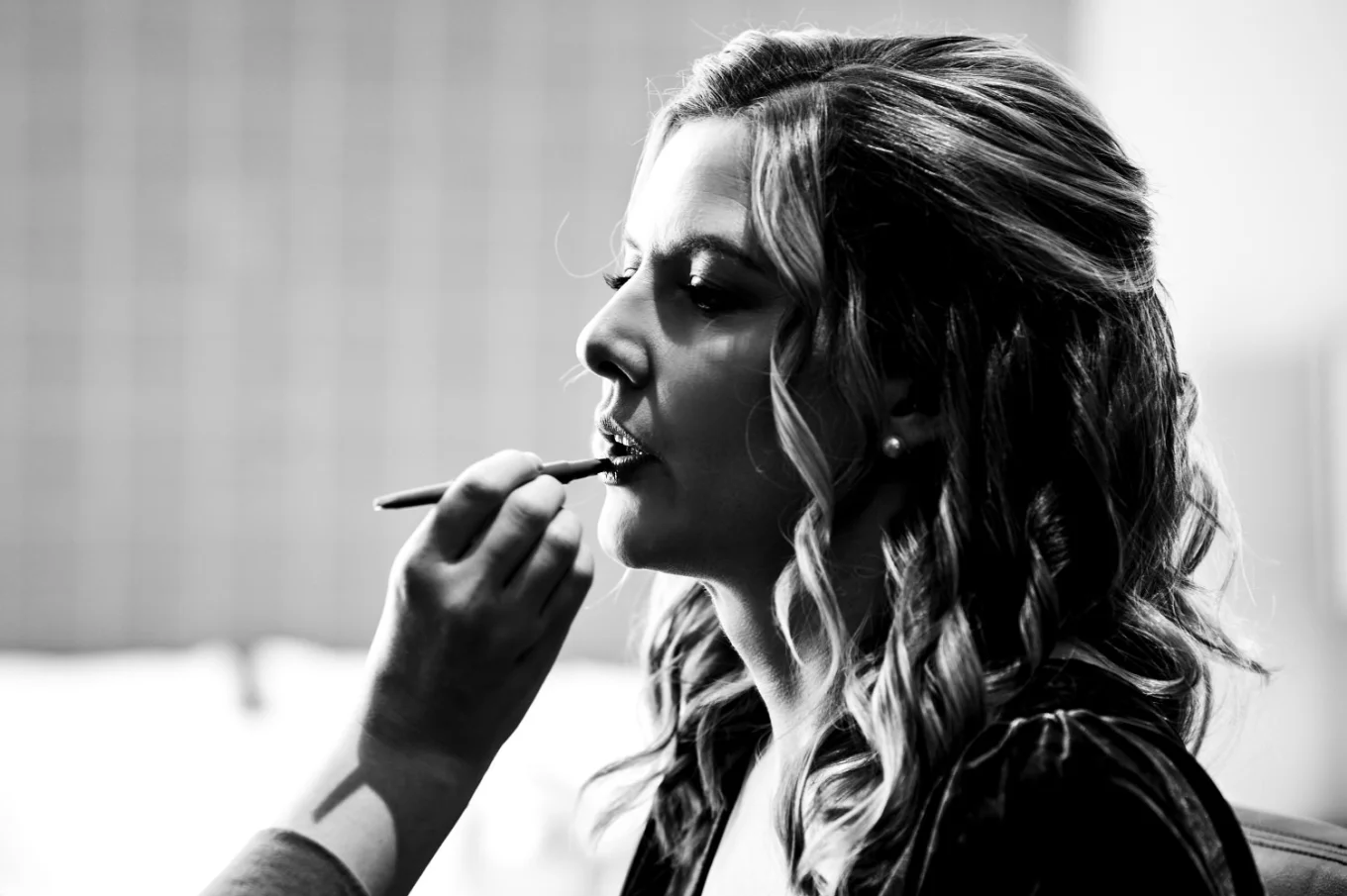 make up artists hand put a lipstick on the bride's lips
