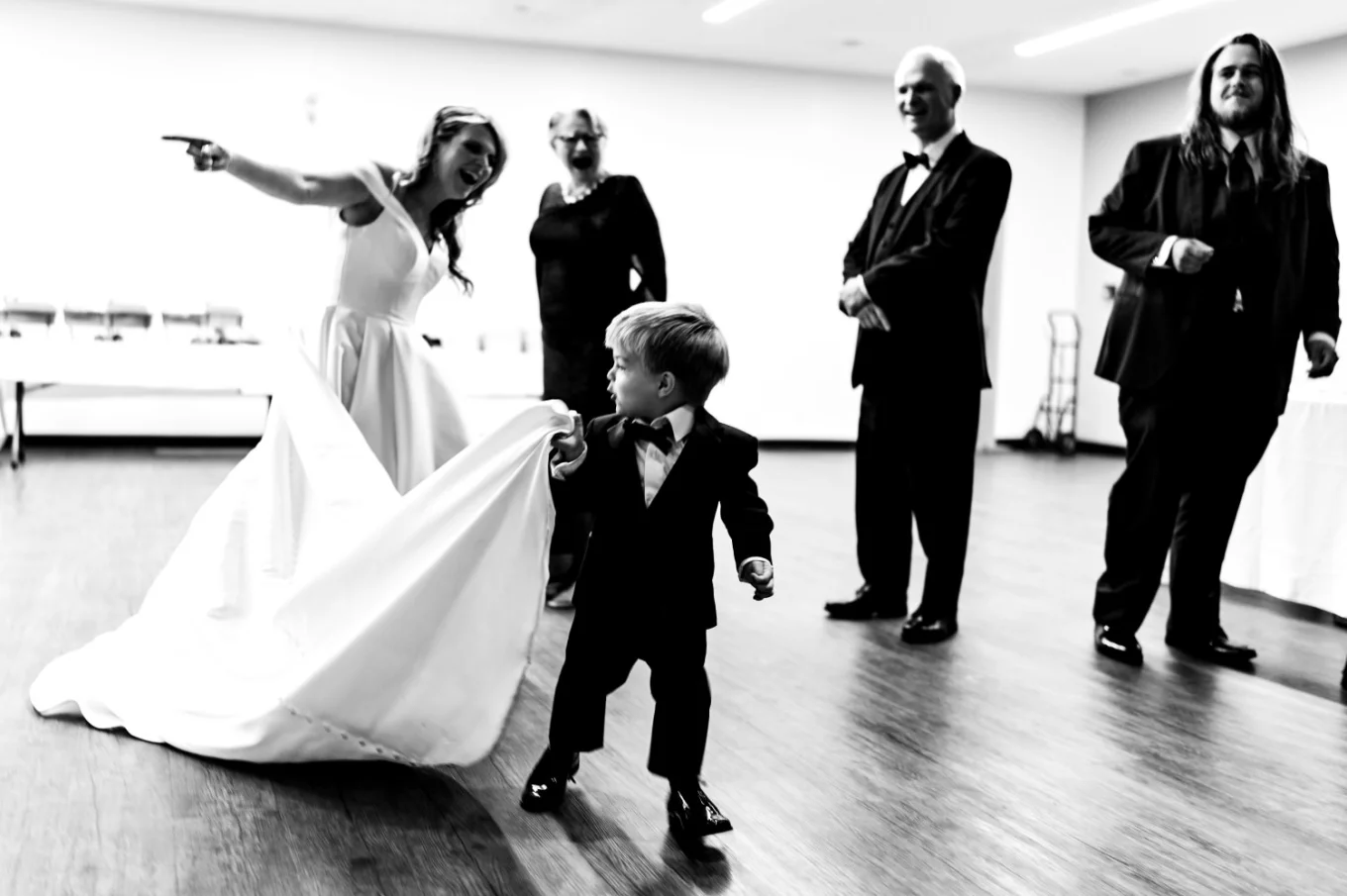 Son of the bride pulling her wedding dress.