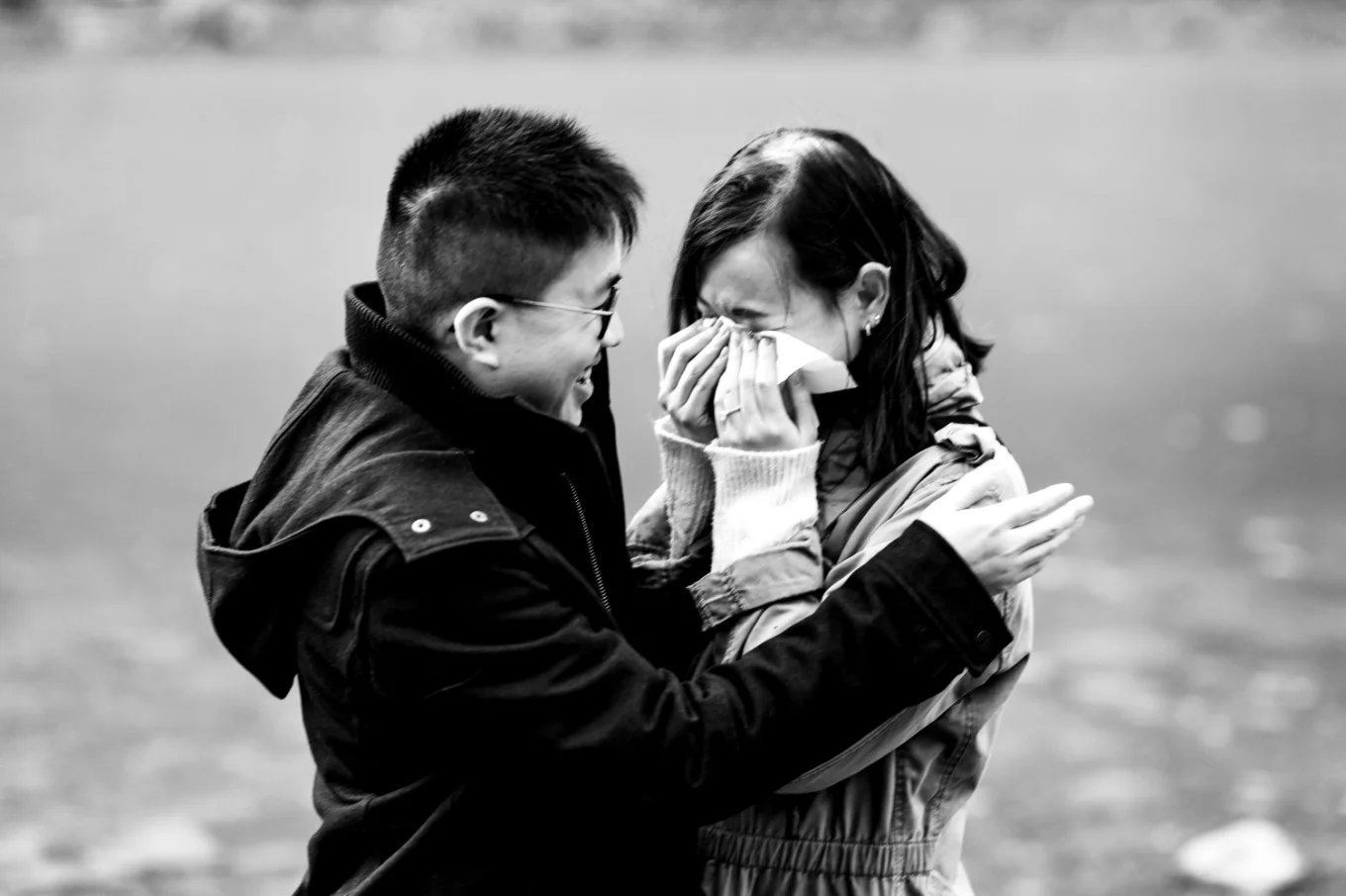 Lady cries and whiles her eyes when her fiancee proposed. He hugs her.