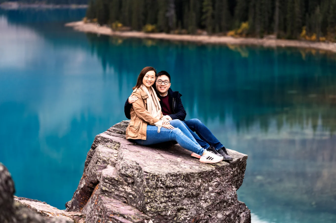 Engaged couple sits at the huge rock at Moraine Lake