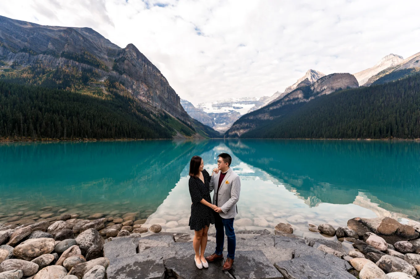 Banff Engagement Photography of couple in love holding hands at turquoise Lake Louise