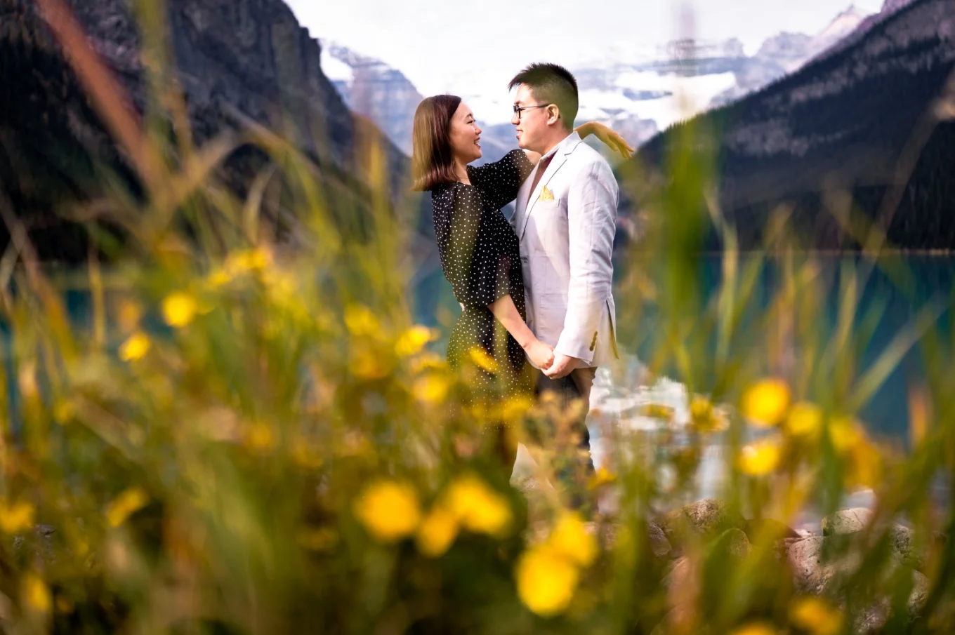 Young couple in love look at each other surrounded by yellow flowers.