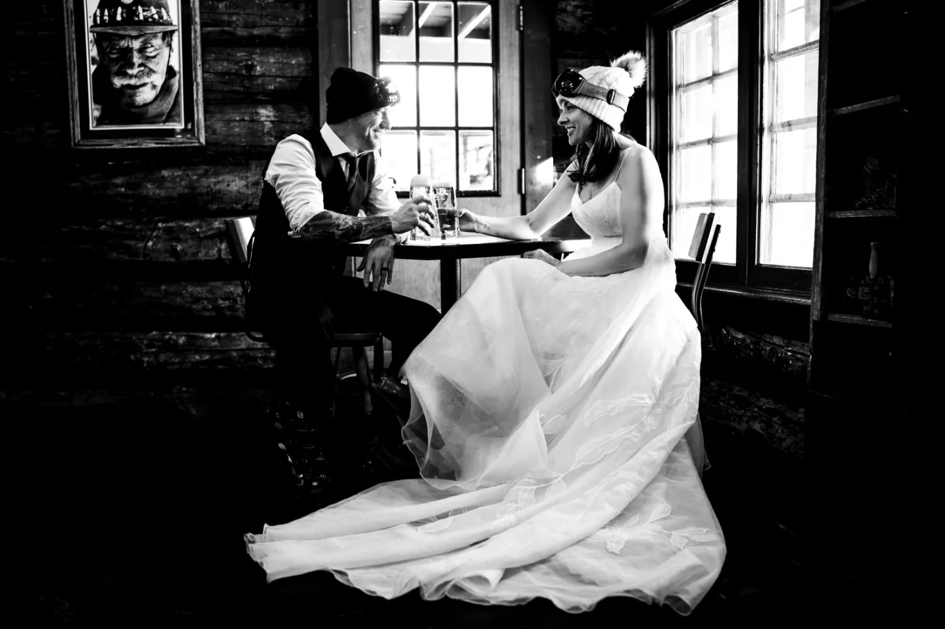 Bride and groom sit by the table and drink a beer.