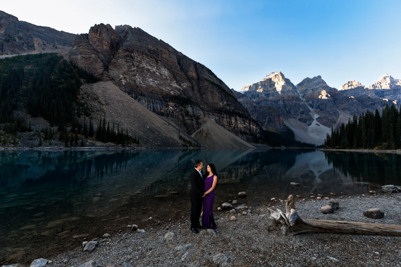 husband and wife looking at each other and hugging at the shore of Moraine Lake in Banff