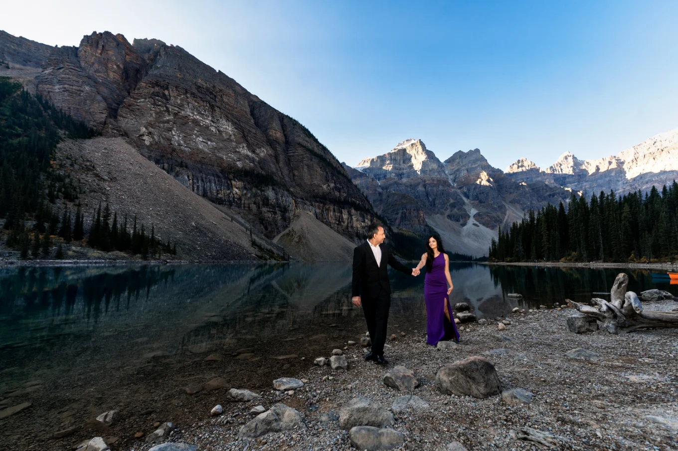 Couple in love walk at the shore of Moraine Lake and hold their hands.