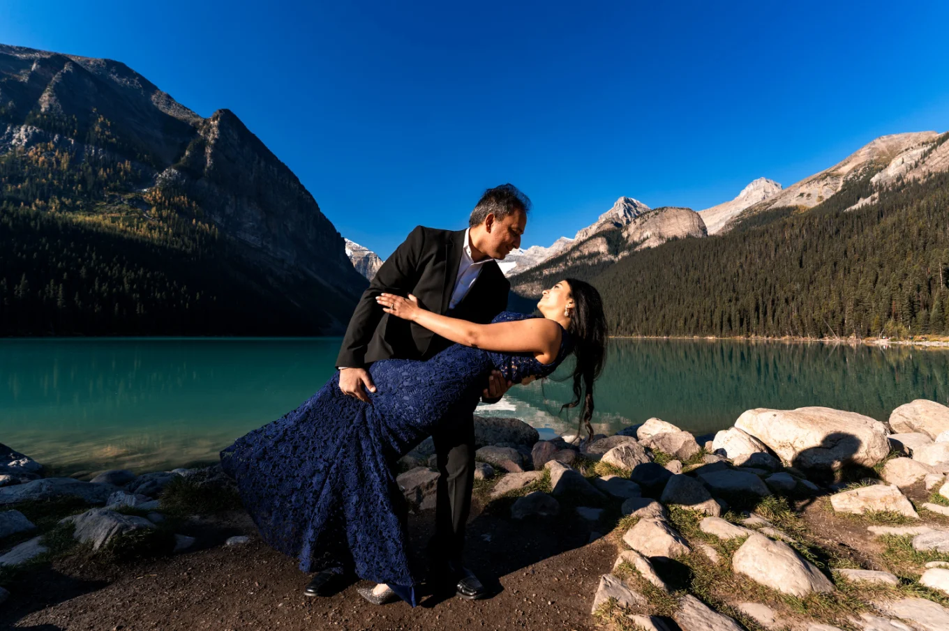 Man dips her wife during their dance at Lake Louise.