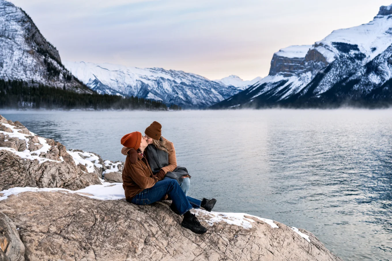 Banff Engagement Photograohy of the couple in love sitting at the shore of Minnewanka Lake.
