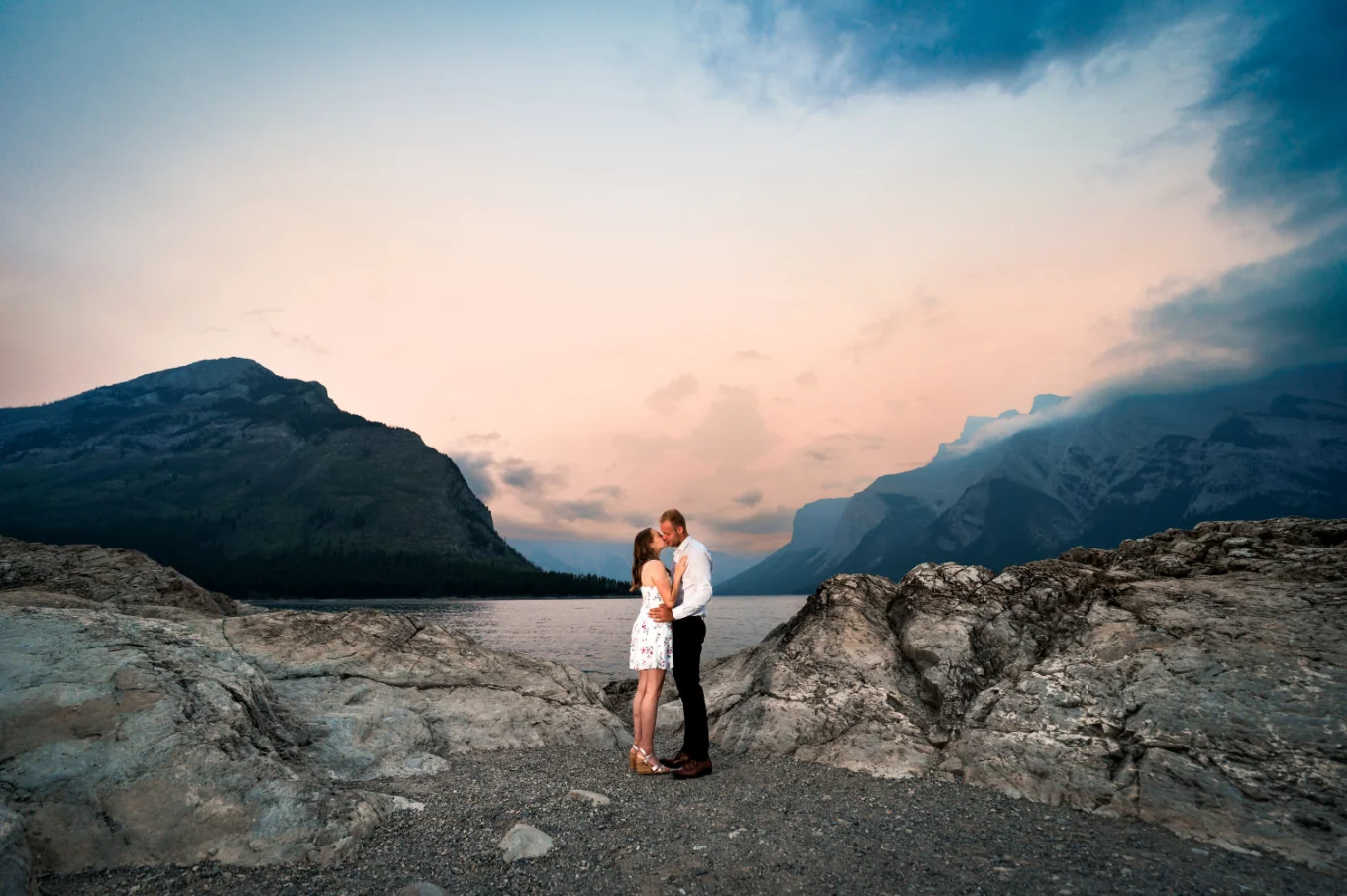 young couple share a kiss at the shore of Minnewanka Lake