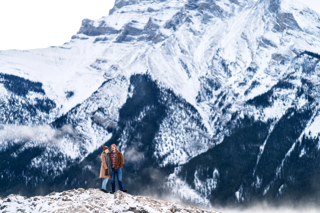 Banff Engagement Photography of the couple in a hug against a huge mountain.