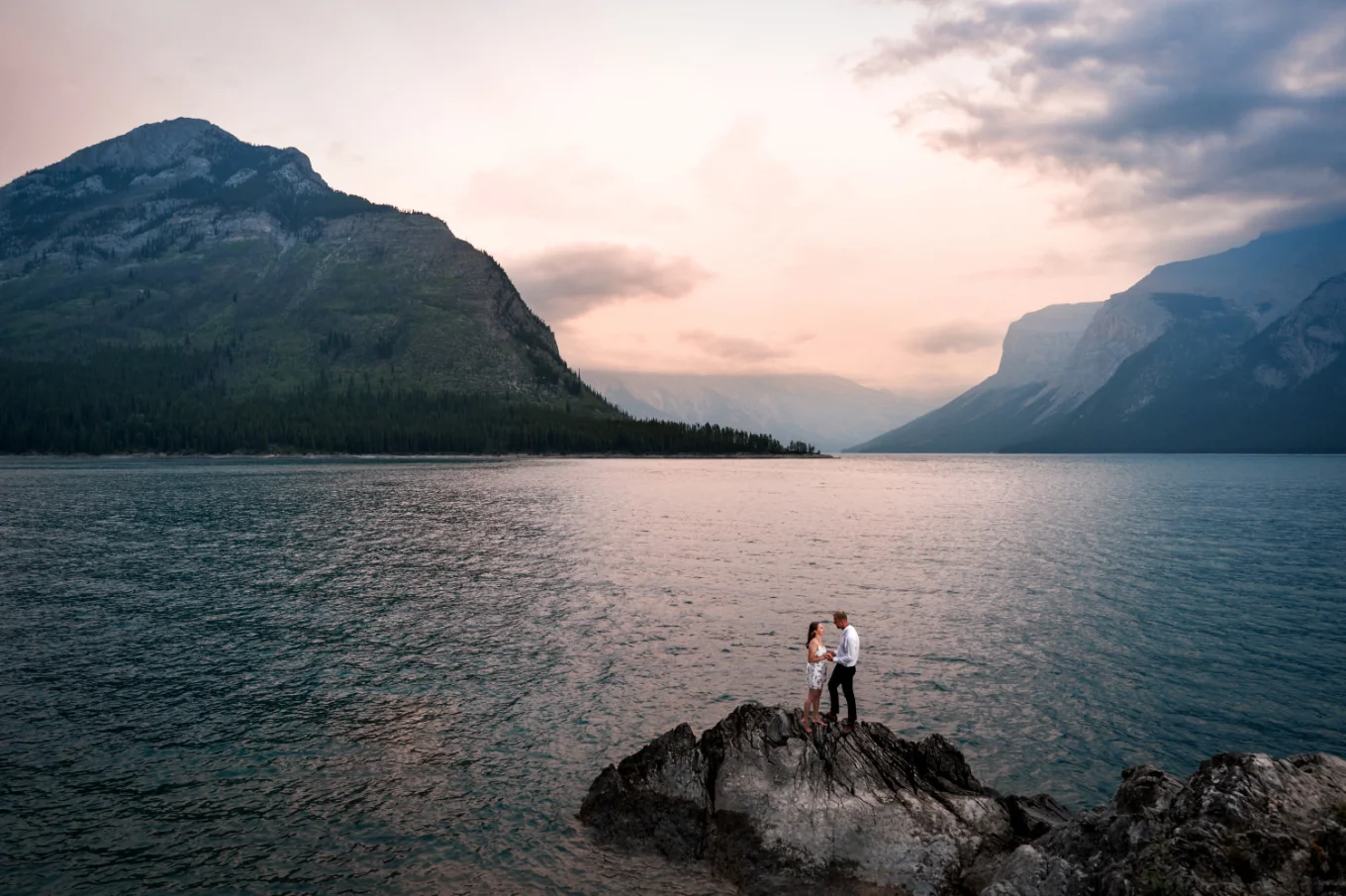 couple in love standing on the small isand at Minnewanka Lake during sunrise