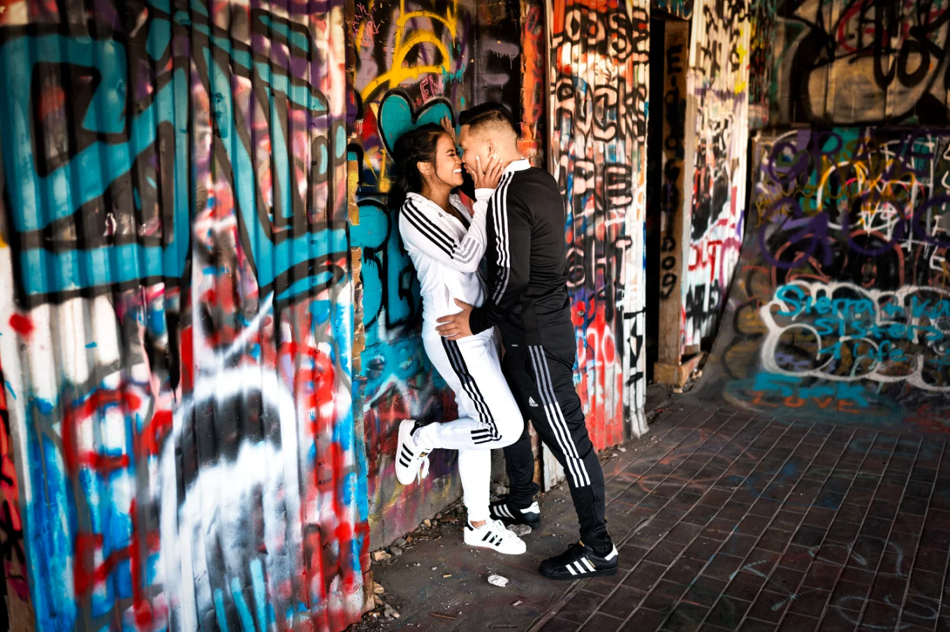 Couple in love lean over a wall an an old building with graffiti.