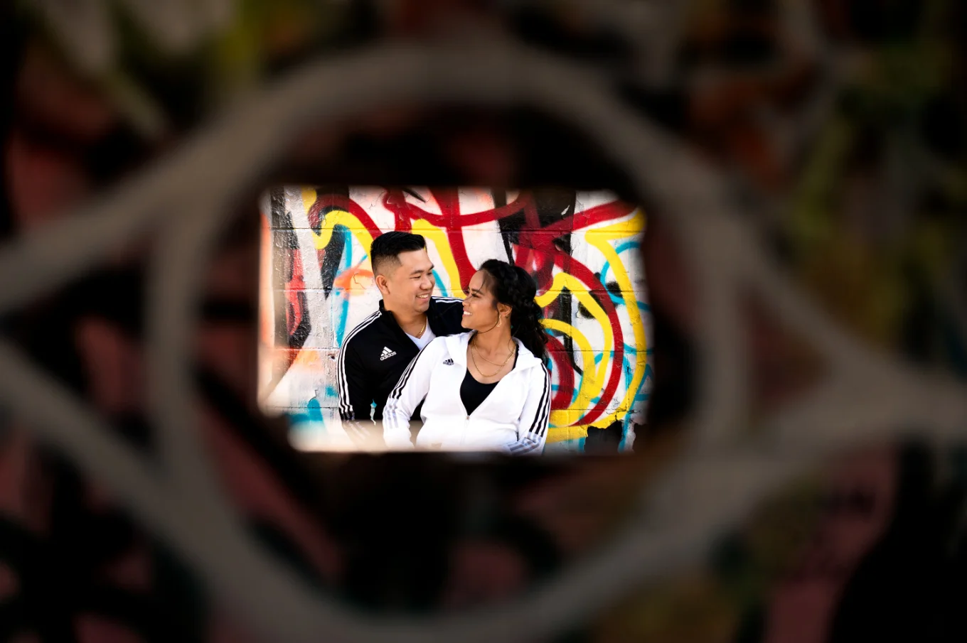 Shoot through the whole in wall of the young engaged couple lookin at each other.