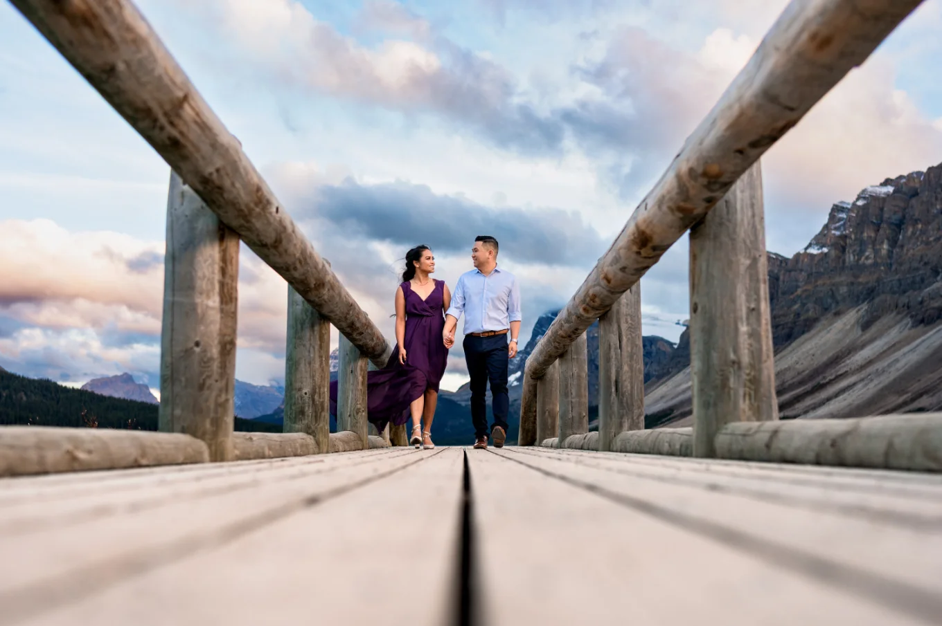 Young well dressed couple walk on the wooden bridge in the Canadian Rockies.