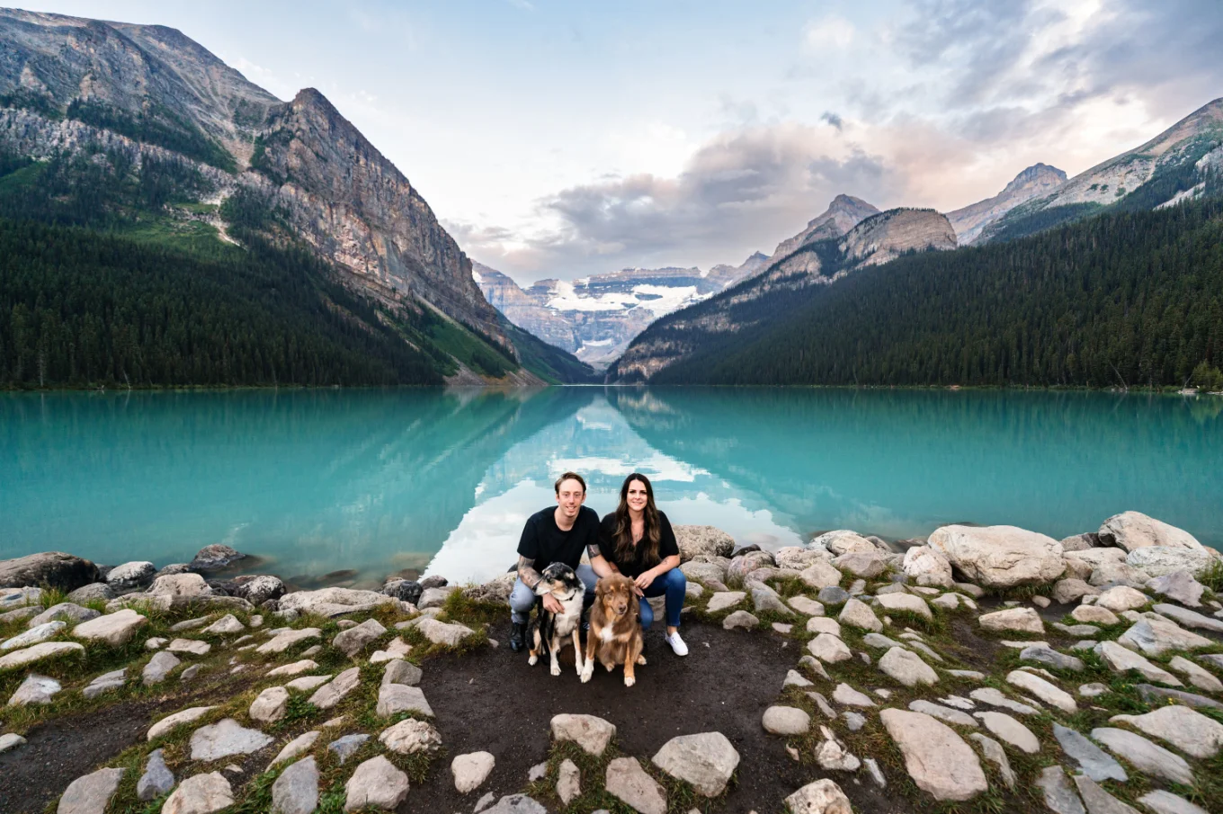 Couple and puppies in love with each other at the shore of blue Lake Louise.