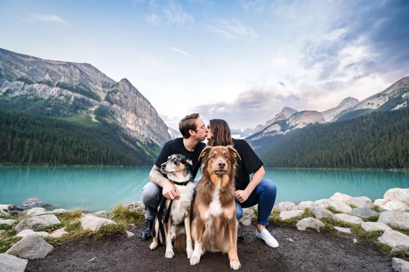 Creative Lake Louise Photography of the kissing couple in front of their cute puppies.