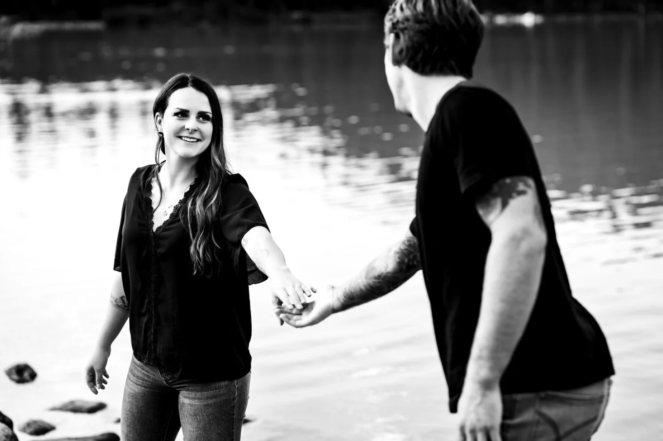 A Man helps his fiancee and gives her hand at the lake.