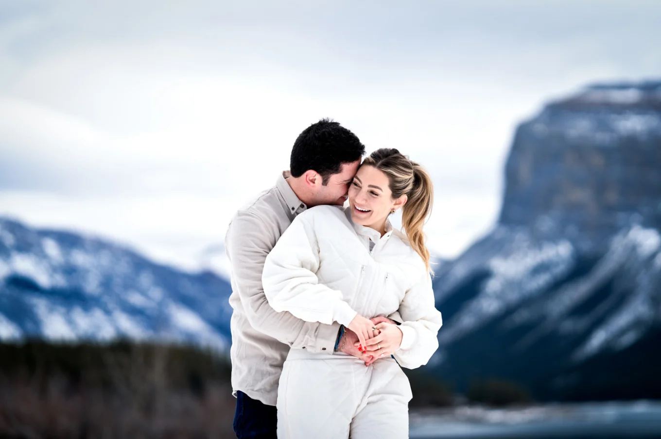 Man hugs his fiance from behind in the mountains