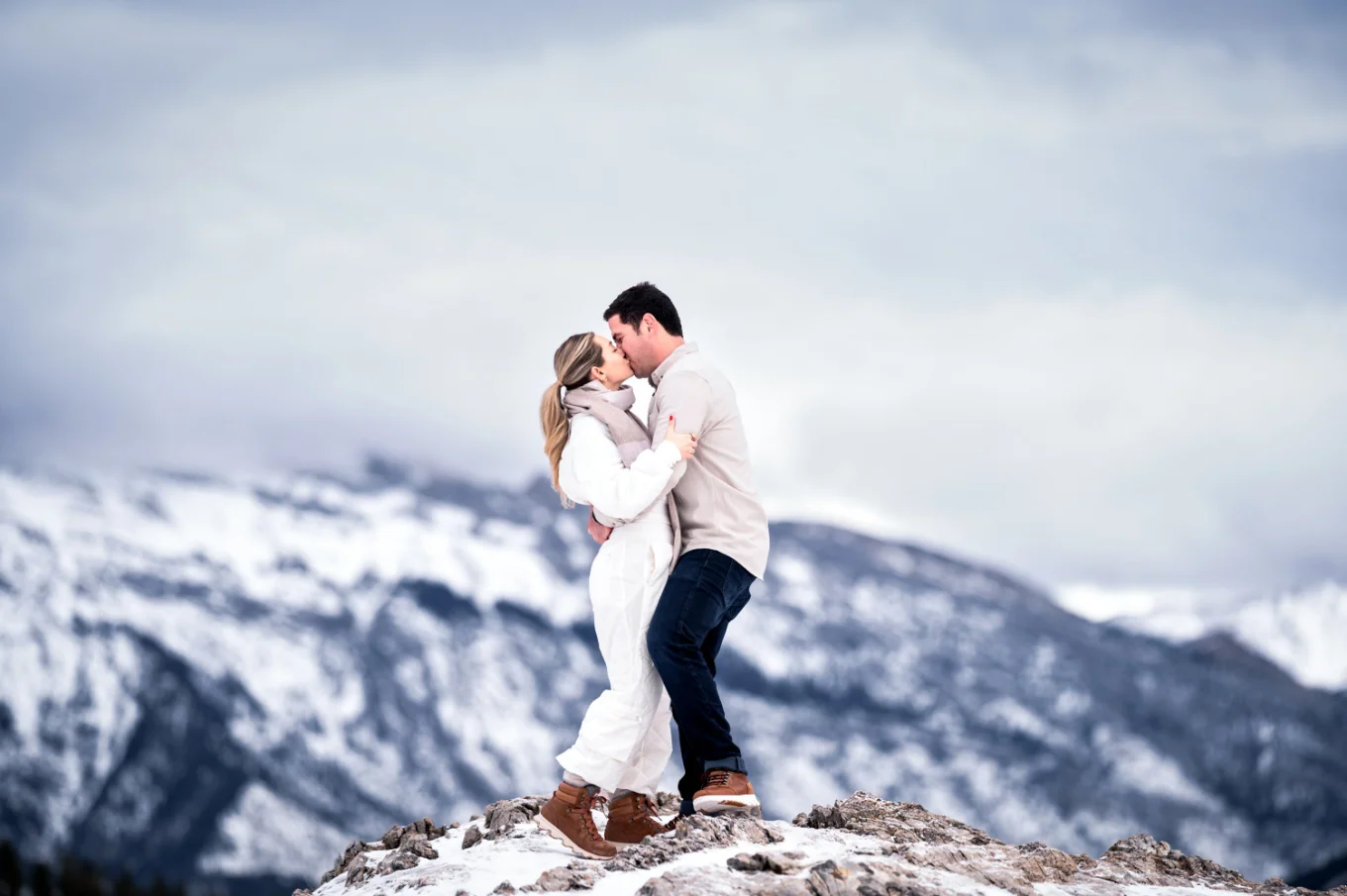 Couple in love share w kiss against Rocky Mountains