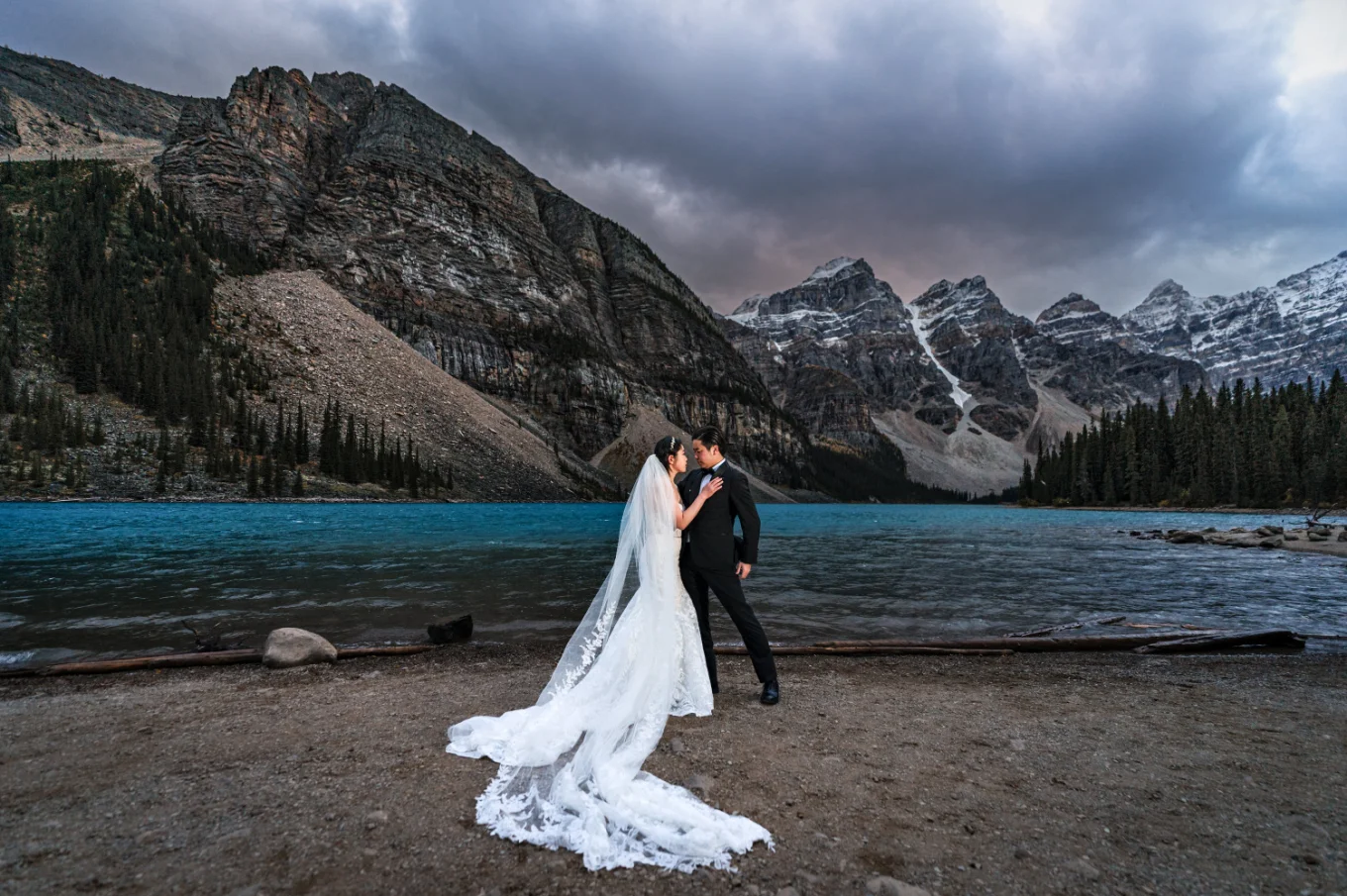 Bride and groom stand at the lakeshore at Moraine Lake