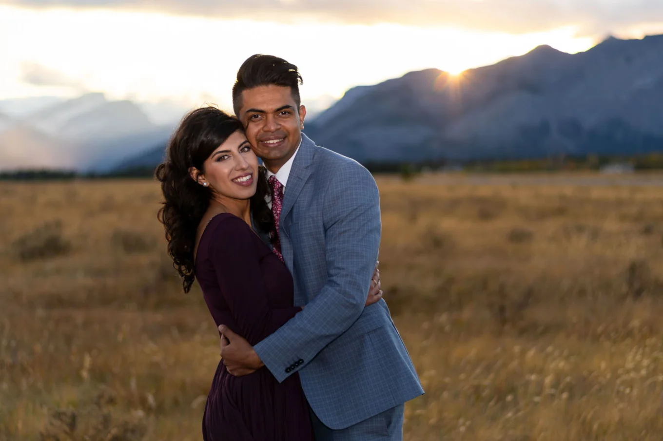 Engaged couple hugging each other with a smile on their faces.