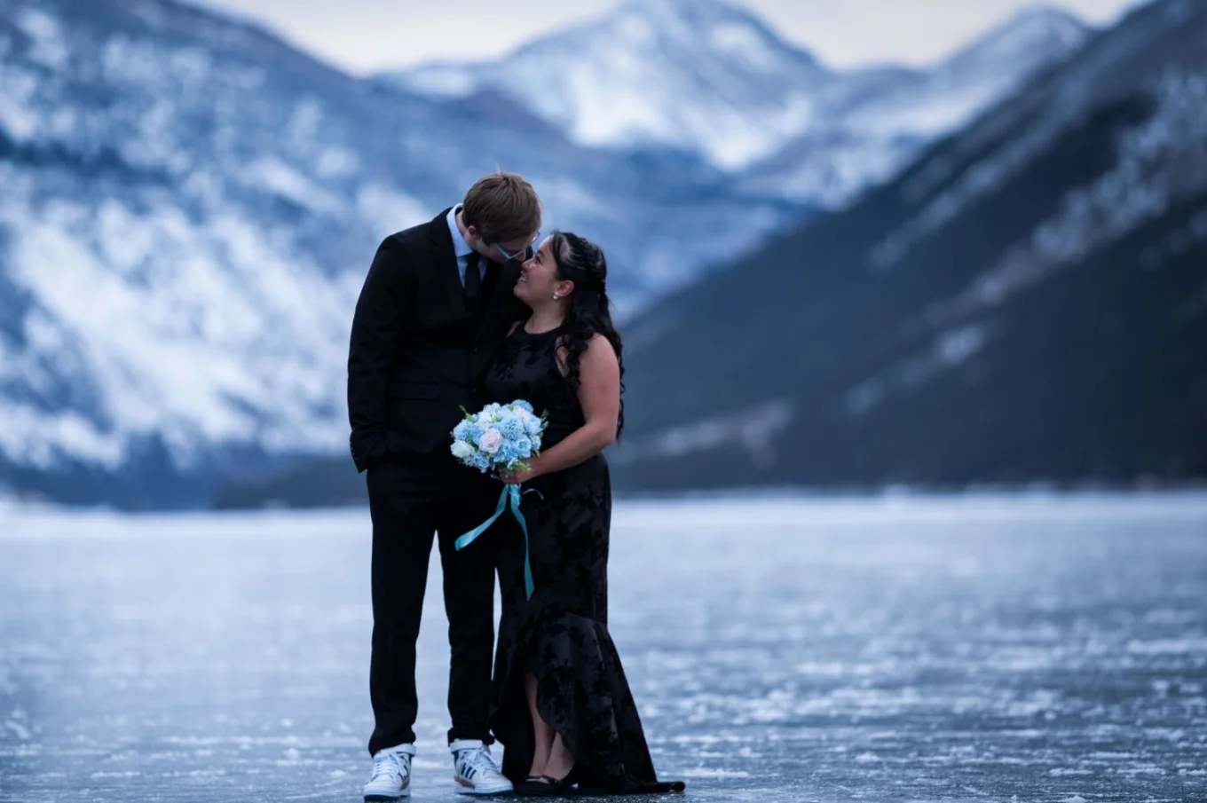 People in love look at each other. The girl holds blue flowers from her fiancée.