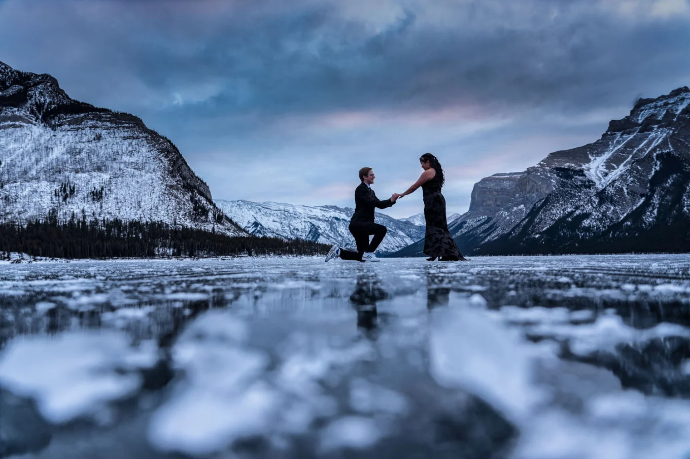 Surprise engagement at frozen Minnewanka Lake in Banff.