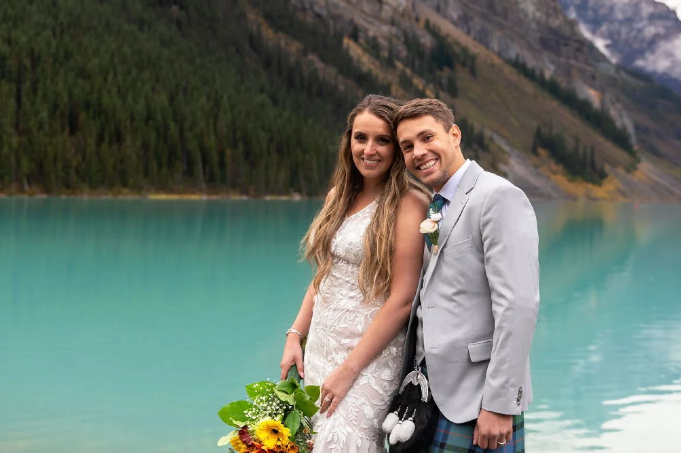 Happy bride and groom smiling at the camera during their elopement at Lake Louise.