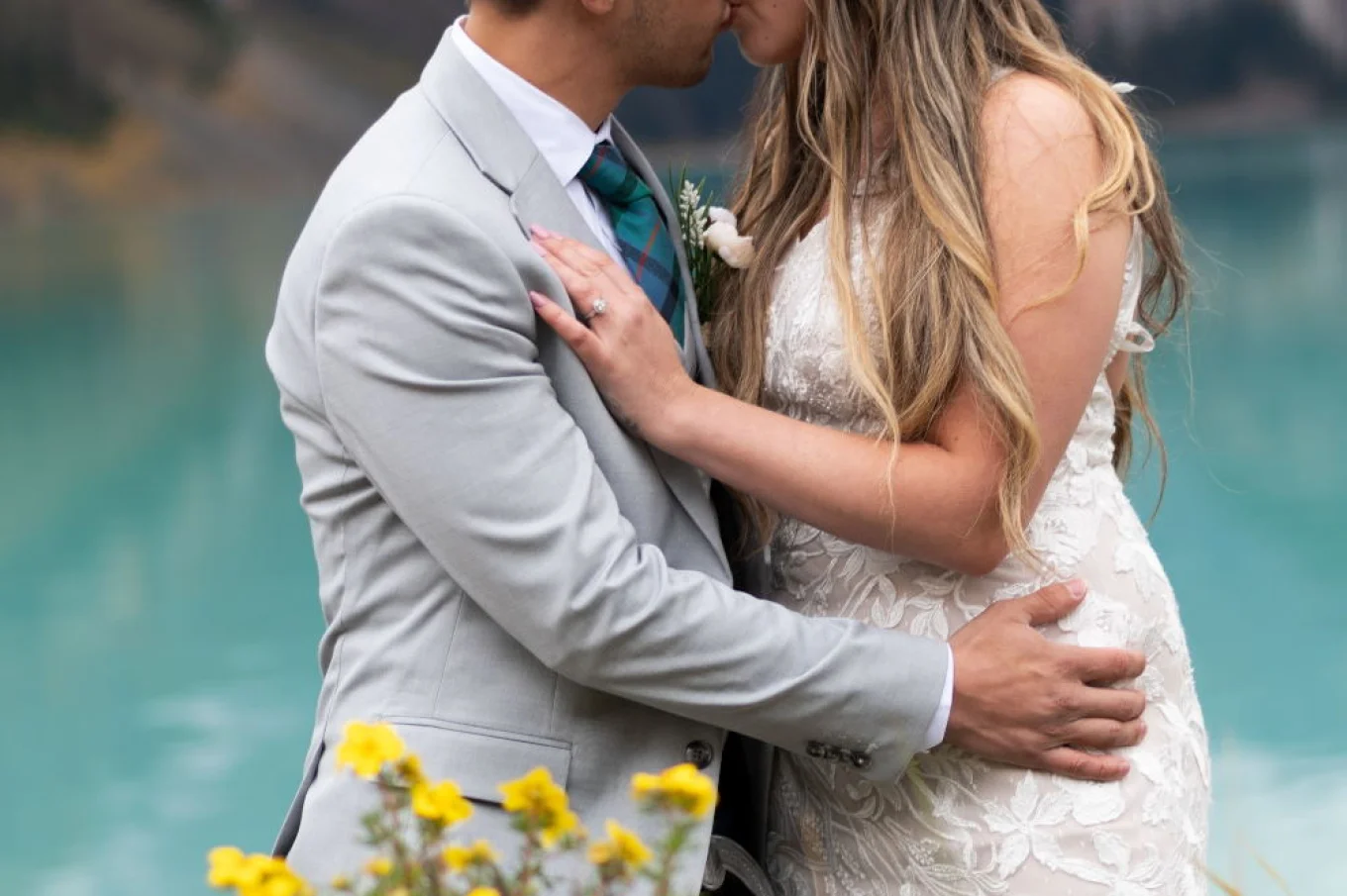 Bride and groom kissing at turquoise Lake Louise