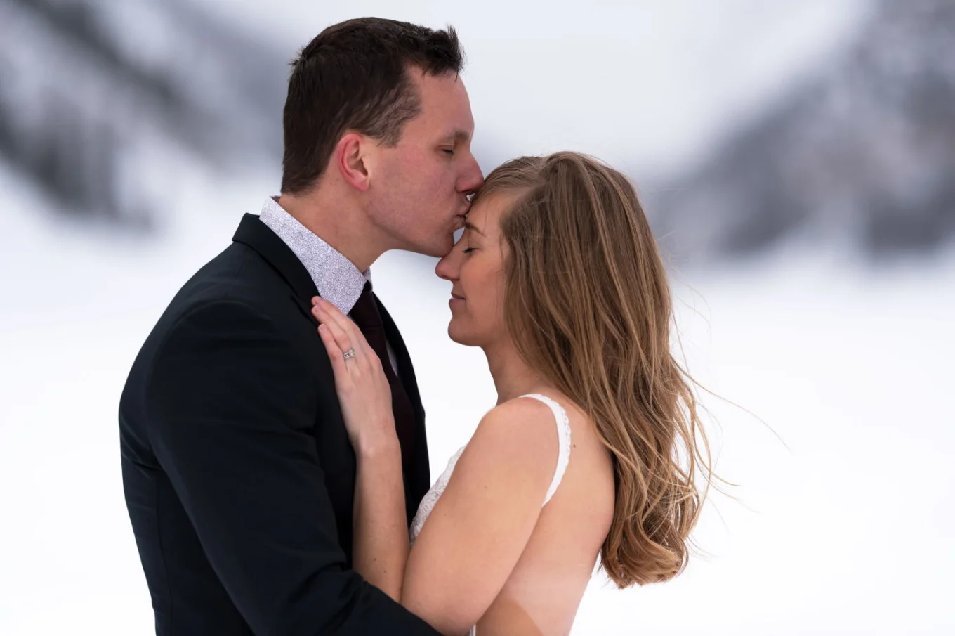 groom is kissing the bride's forehead