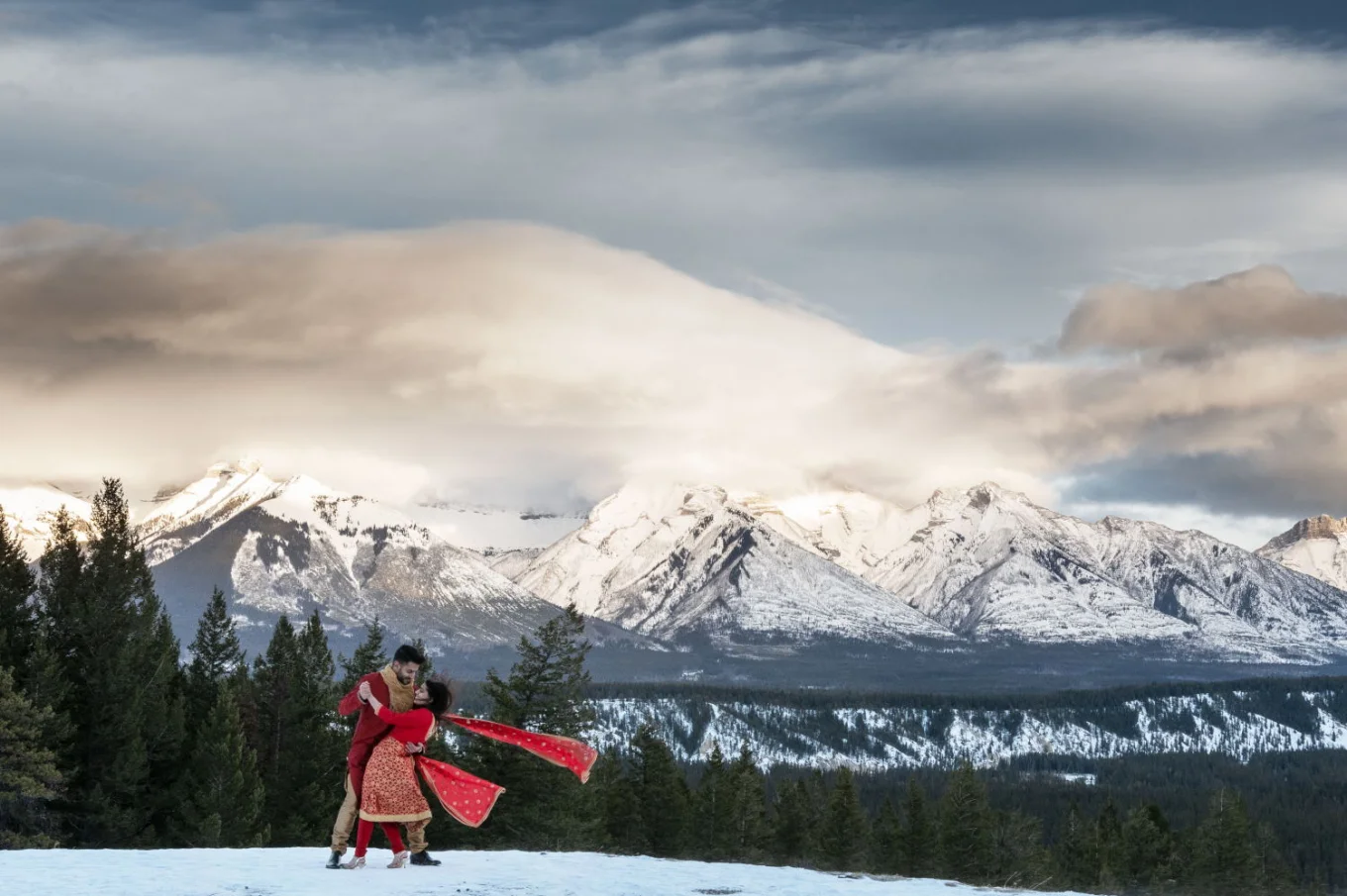 Married couple perform traditional Indian dance during their after wedding photo session in Banff.