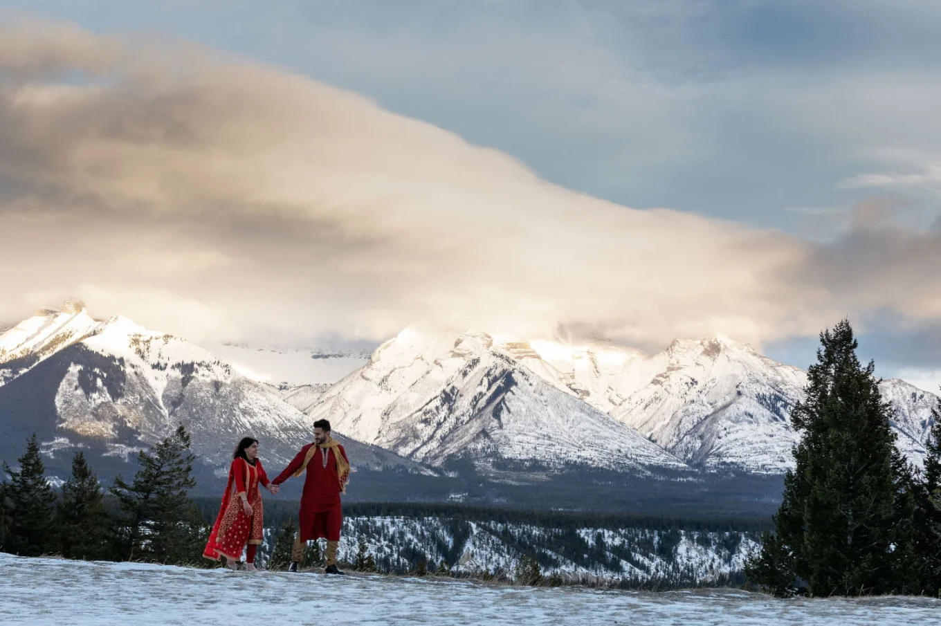Indian wedding in Banff. Couple walking it their red indian wedding outfits in Banff.