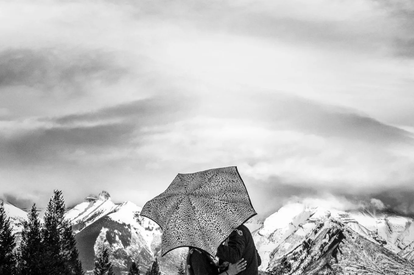 Grom and bride are kissing under an umbrella.