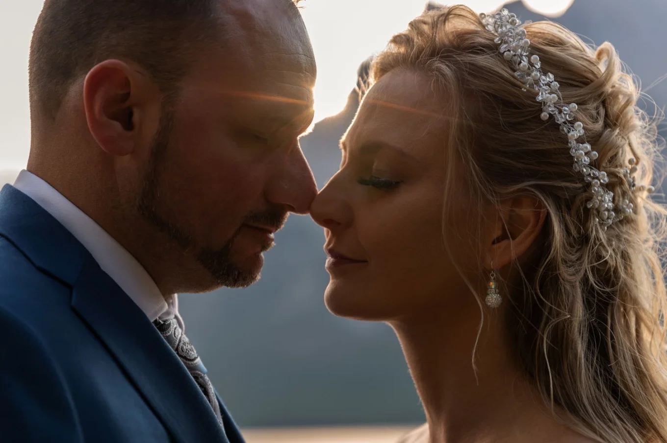 Newly married couple touching theis noses. Rays of the sun between their heads. Romantic after wedding photo shoot in Banff.