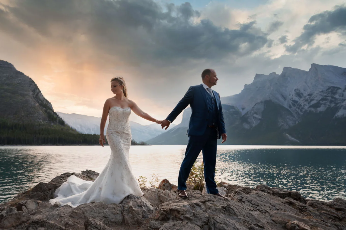 After wedding session at Lake Minnewanka during stunning sunrise. Marrieg couple holding hands.