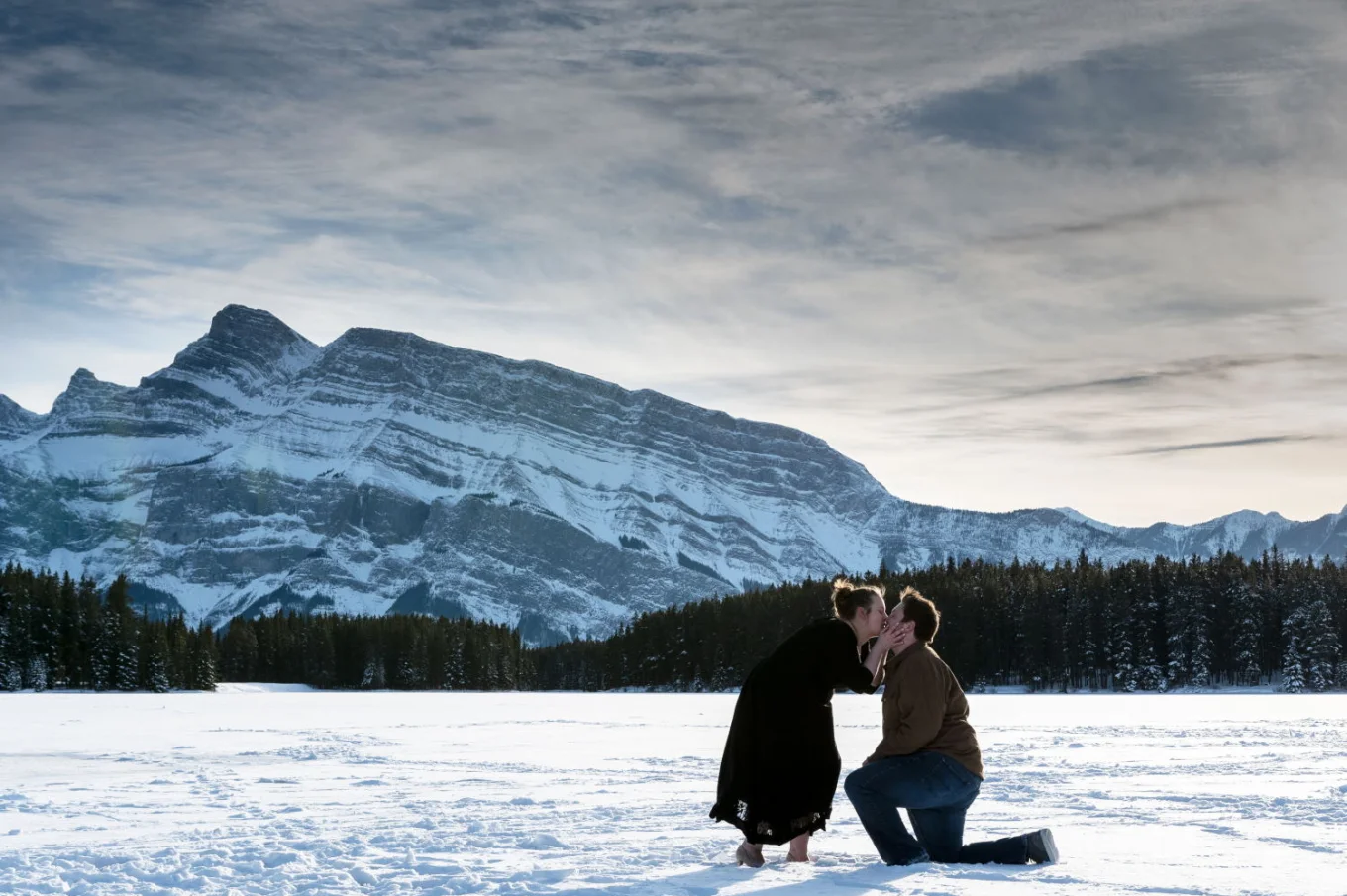 A woman is kissing his fiance after his marriage proposal in Banff.