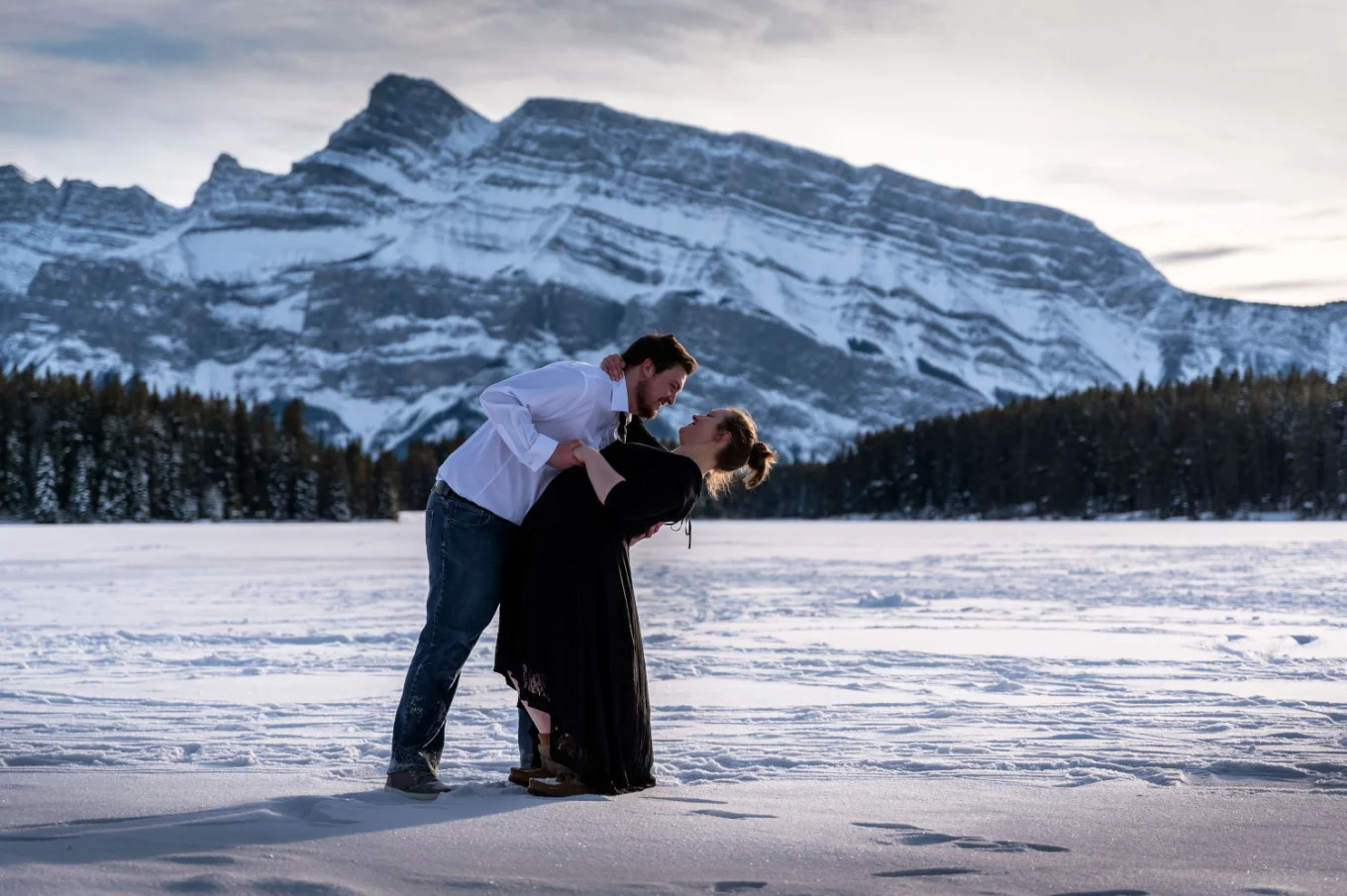 Winter engagement photo session in Banff. Engagement couple is dancing at the frozen lak.
