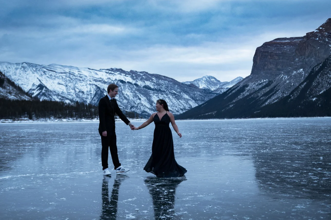 Newly engaged couple is dancing at the frozen lake in Banff during their engagement session.