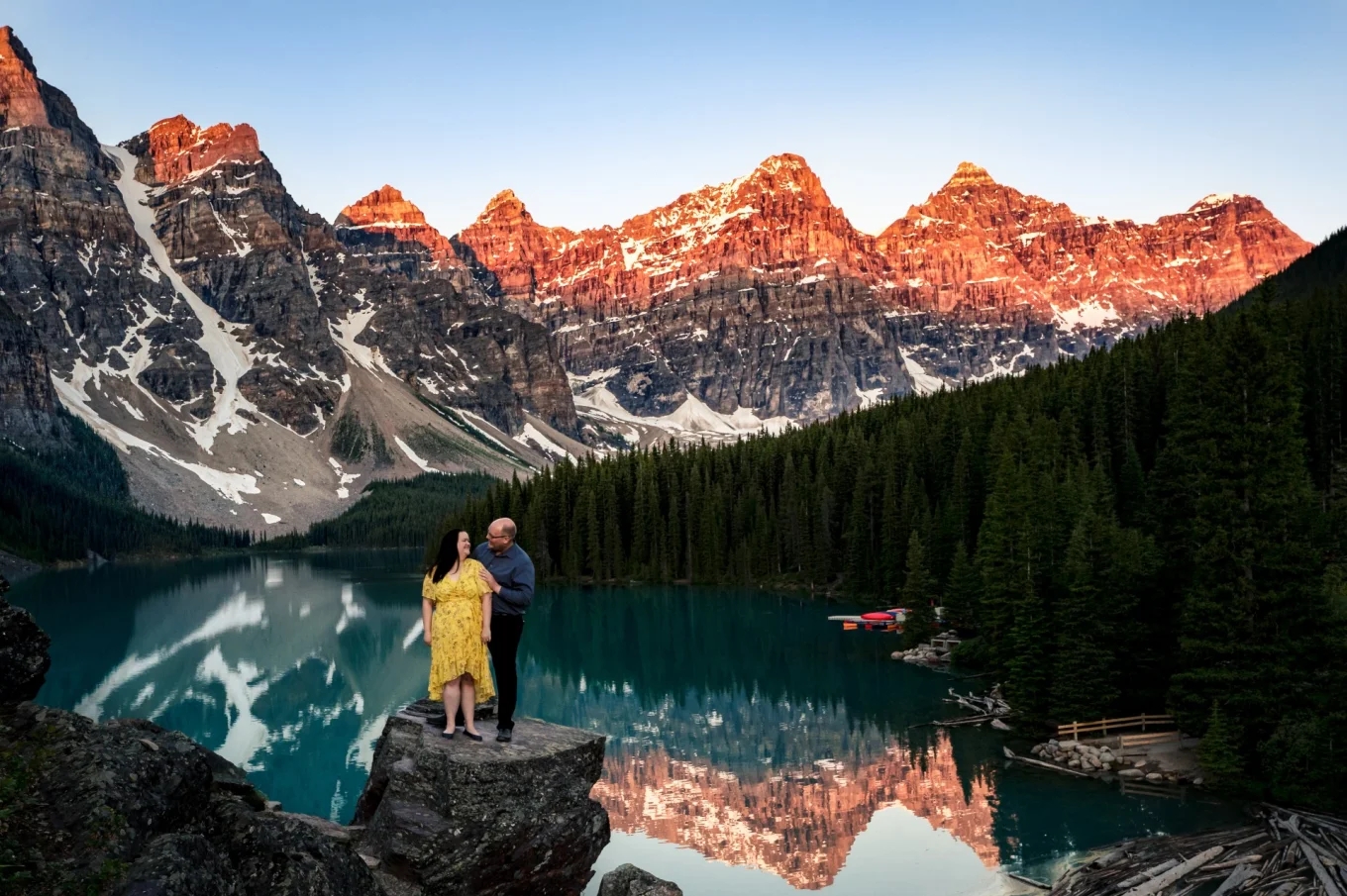 Couple standing at the rock at Moraine Lake surrounded by Rocky Mountains