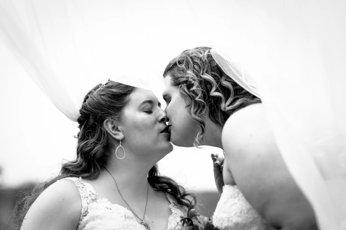 Same sec couple are kissing under the veil. Calgary Wedding Photography.