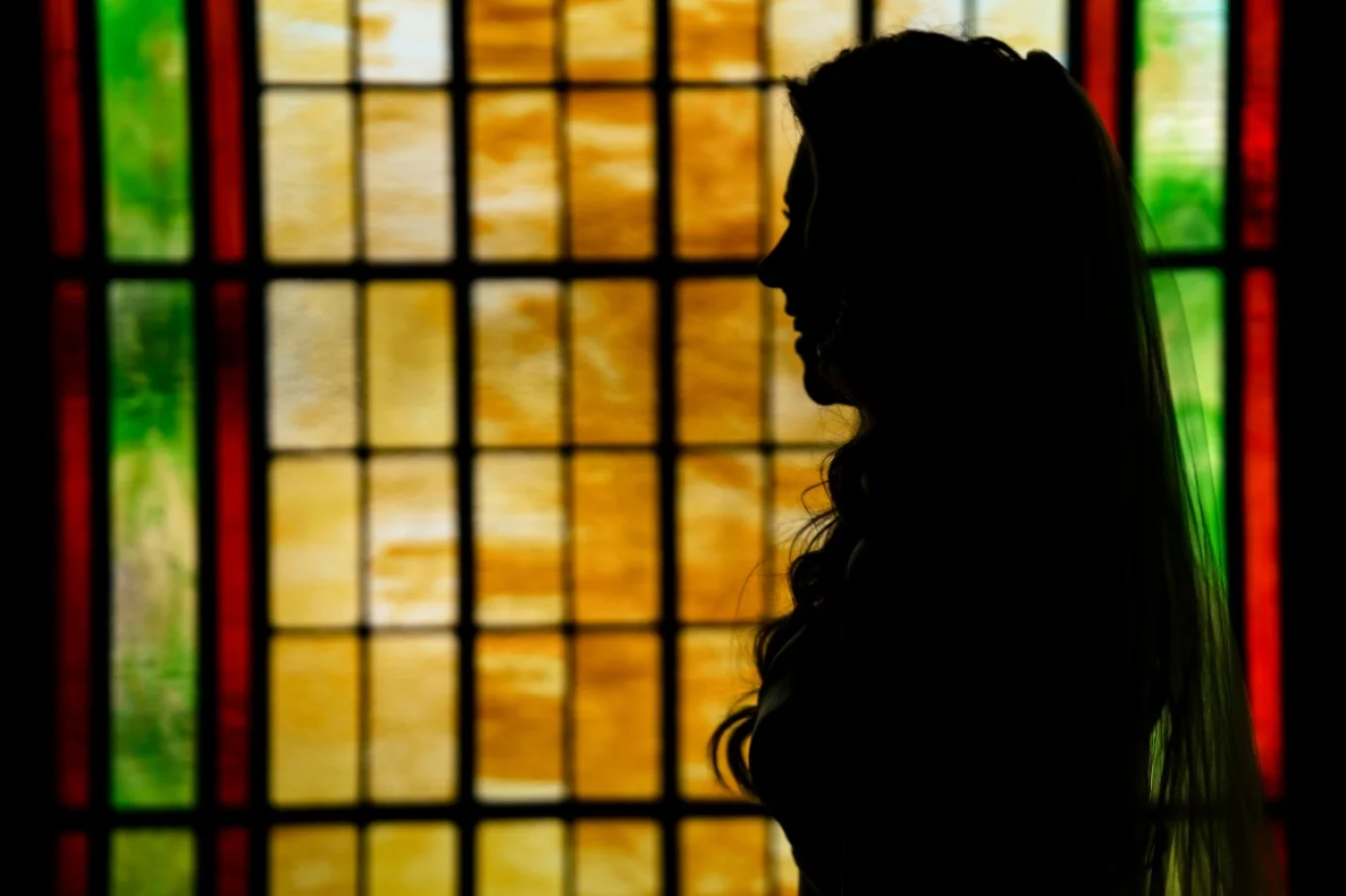 Bride's Portrait by stained glass during Calgary Wedding Ceremony in the church